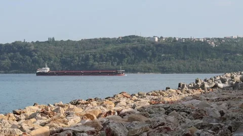 Cargo barge navigating calm sea waters near a rocky coast Stock Footage 341787655
