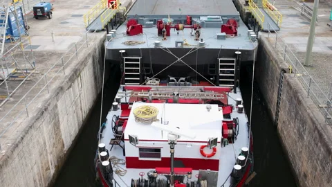 Cargo barge navigating canal lock chamber between concrete walls industrial Stock Footage 328979507
