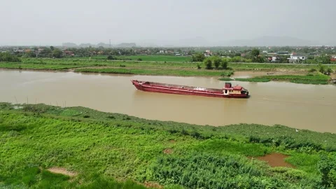 Cargo barge navigating a muddy river through the rural vietnam landscape of.. Stockbeeldmateriaal 335087818