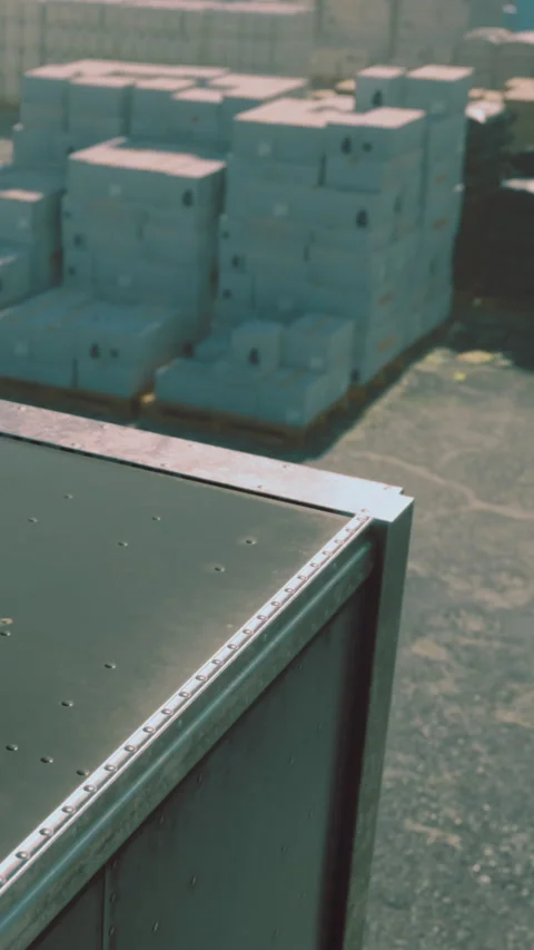 Cargo container resting on a sunlit dock surrounded by stacked boxes Stock Footage 330270643