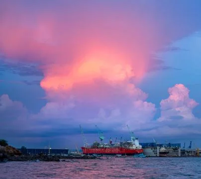 Cargo container ship at dry dock for maintenance service on red storm backgro Stock Photos