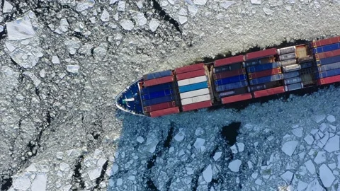 Cargo container ship running through the ice floe, top down aerial view. Stock Footage 170384897