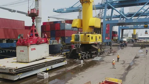 Cargo containers being loaded at a busy shipping port with cranes and trucks Stock Footage 318206443