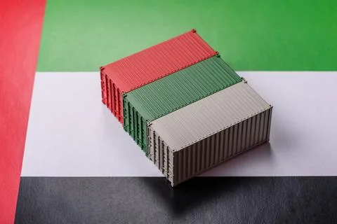 Cargo containers on the UAE flag as a conceptual backdrop for goods export... Stock Photos