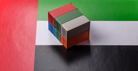 Cargo containers on the UAE flag as a conceptual backdrop for goods export... Stock Photos