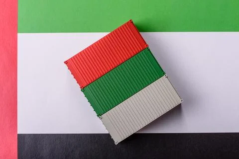 Cargo containers on the UAE flag as a conceptual backdrop for goods export... Stock Photos