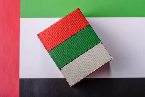 Cargo containers on the UAE flag as a conceptual backdrop for goods export... Stock Photos
