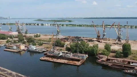 A cargo crane unloads sand from a barge at a river port on a sunny summer day Stock Footage 137028894