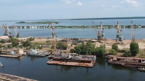 A cargo crane unloads sand from a barge at a river port on a sunny summer day Stock Footage 137028959