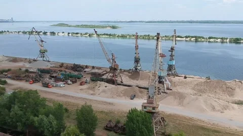 A cargo crane unloads sand from a barge at a river port on a sunny summer day Video stock 137029068