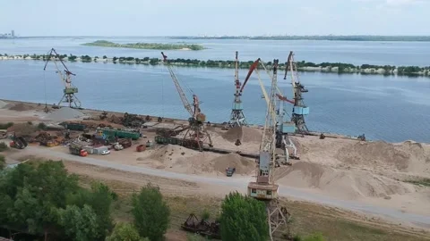 A cargo crane unloads sand from a barge at a river port on a sunny summer day Stock Footage 137029433