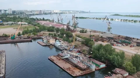 A cargo crane unloads sand from a barge at a river port on a sunny summer day Stock Footage 137029542