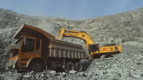 Cargo dump truck being loaded in a mining quarry. Yellow excavator loads mineral Stock Footage 221637320