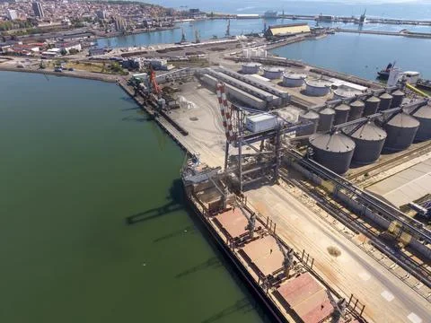 Cargo loading at a port with ships and industrial structures Fotos de archivo