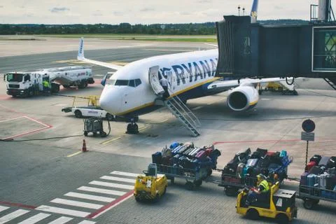 Cargo luggage being driven towards a Ryanair aeroplane on the runway at airport Stock Photos
