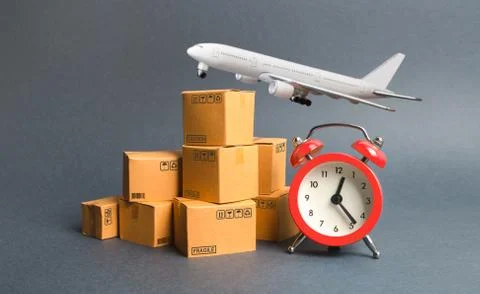 Cargo plane, stack of cardboard boxes and a red alarm clock. Express air deli Stock Photos