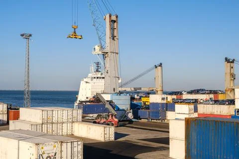 Cargo port busy with loading a bulk carrier, crane and reach stacker working Stock Photos