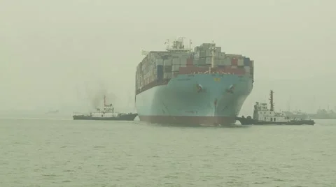 Cargo ship being turned by tugs Stock Footage 1079222