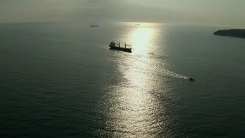 Cargo ship calling into the port under the guide of tugboat. Sunset lights the s Stock Footage 154468391