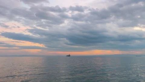 Cargo Ship on Calm Sea at Sunset with Dramatic Cloudy Sky Background Footage Stock Footage 339504992