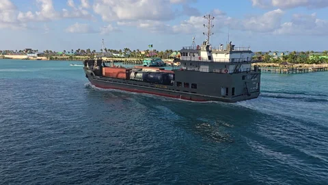Cargo ship carrying containers and trailers sailing near a tropical coast Stock Footage 341334835