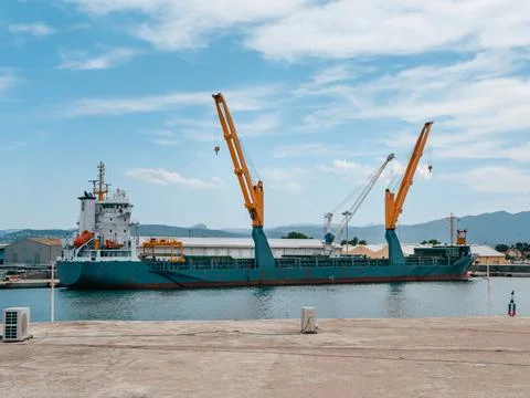 Cargo ship with cranes on loading in the port Stock Photos