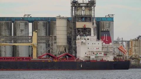 A cargo ship on dock on a factory near the sea Stock Footage