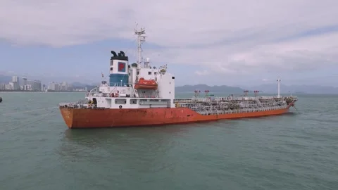 Cargo ship docks at harbor under clear skies in coastal city Stock Footage 308245913