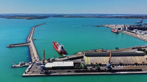 Cargo ship docks at port in sunny weather with clear blue water Stock Footage 339158094