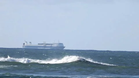 Cargo Ship Far Away on the Sea passing through some crashing Waves Stock Footage 213603536