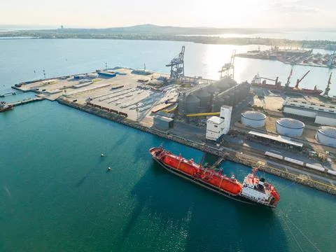 Cargo ship at a harbor with shipping containers and cranes near the water d.. Stock Photos