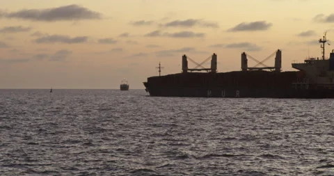 Cargo ship on horizon with soft sunset clouds Stock Footage 328999665
