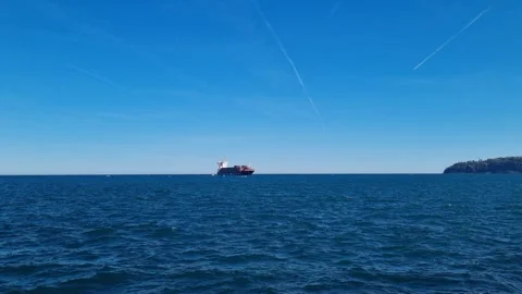 Cargo Ship on Horizon Under Blue Sky and Calm Sea Stock Footage 320735997