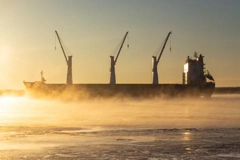 Cargo ship, ice classed bulk carrier in the ice and fog of a freezing river. Stock Photos