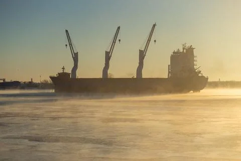 Cargo ship, ice classed bulk carrier in the ice and fog of a freezing river. Stock Photos