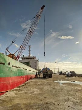 Cargo ship loading and unloading along concrete quay on bright, sunny day 스톡 사진