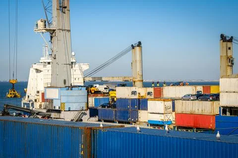 Cargo ship loading containers in commercial port, port crane in operation Stock Photos