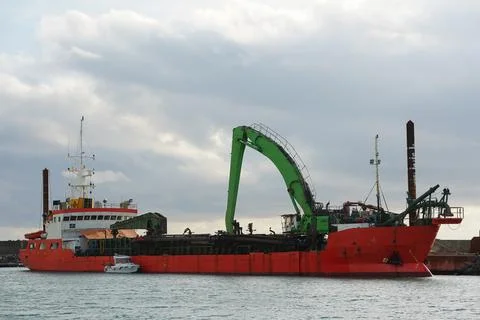 A cargo ship with a loading crane is moored at a seaport Stock Photos