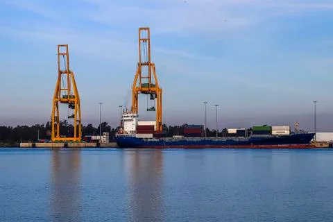 Cargo ship loading. Logistics and transportation with working crane bridge in Stock Photos