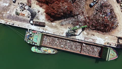 Cargo ship loading metal waste at a recycling facility near a waterfront during 動画素材 337914581