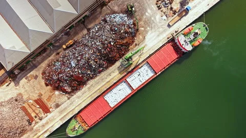 Cargo ship loads scrap metal at industrial port in daytime with facilities and Video stock 341108253