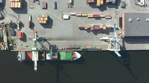 Cargo ship moored at port unloading containers at terminal, aerial top down view Stock Footage 130595322