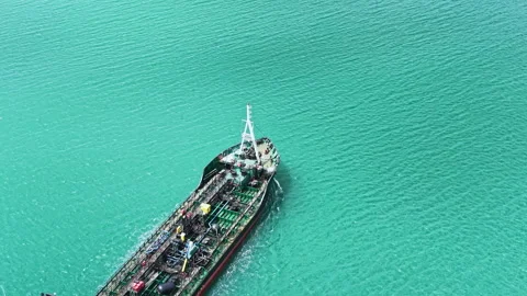 Cargo ship moves slowly in clear blue water near harbor while workers load Vídeos de archivo 337913941