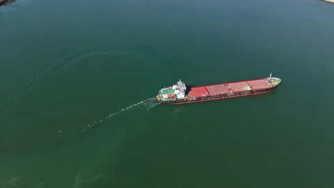 Cargo ship moves through blue water near the shore with another boat nearby Stock Footage 331070236
