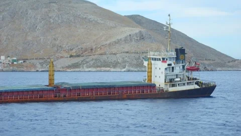 A cargo ship navigating near the coast, with mountainous background in 4K s.. Stock Footage 292759358