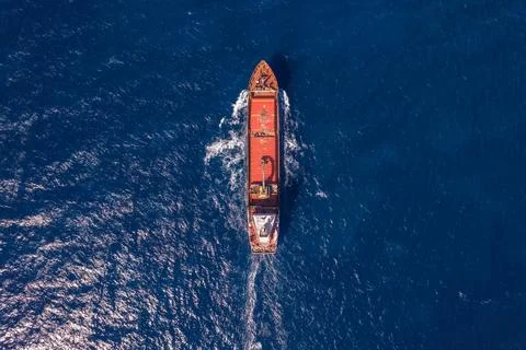 Cargo Ship Navigating Through Deep Blue Sea in Vertical Aerial View Stock Photos
