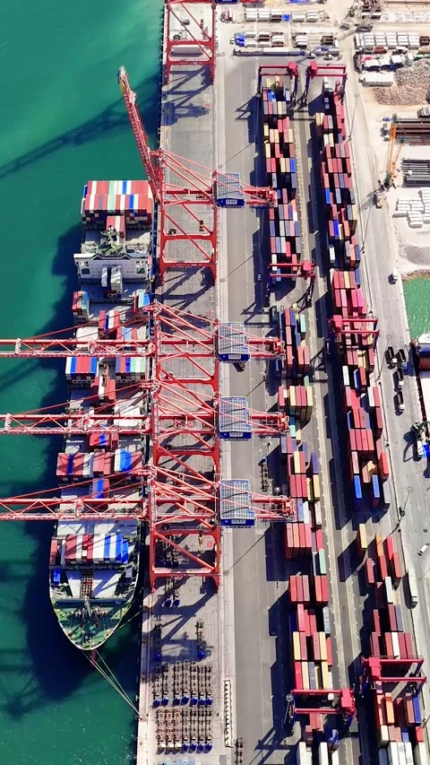 Cargo ship navigating toward a loading dock at an industrial harbor, preparing Stock Footage 288042341