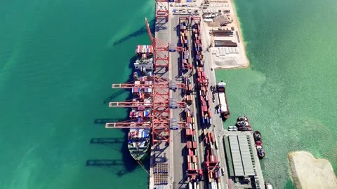 Cargo ship navigating toward a loading dock at an industrial harbor, preparing Video stock 288042460