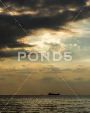 A cargo ship on the ocean under a romantic sky Stock Photos