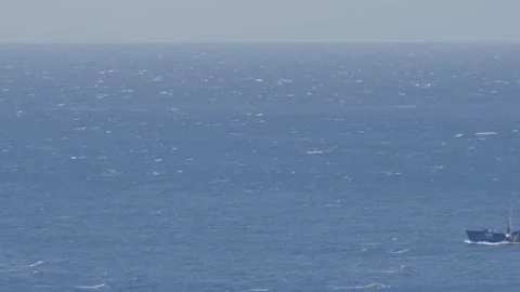 Cargo ship passing by on big ocean waves in the distance Stock Footage 238538450